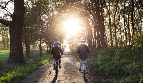 Two children with helmets, biking down a natural path!