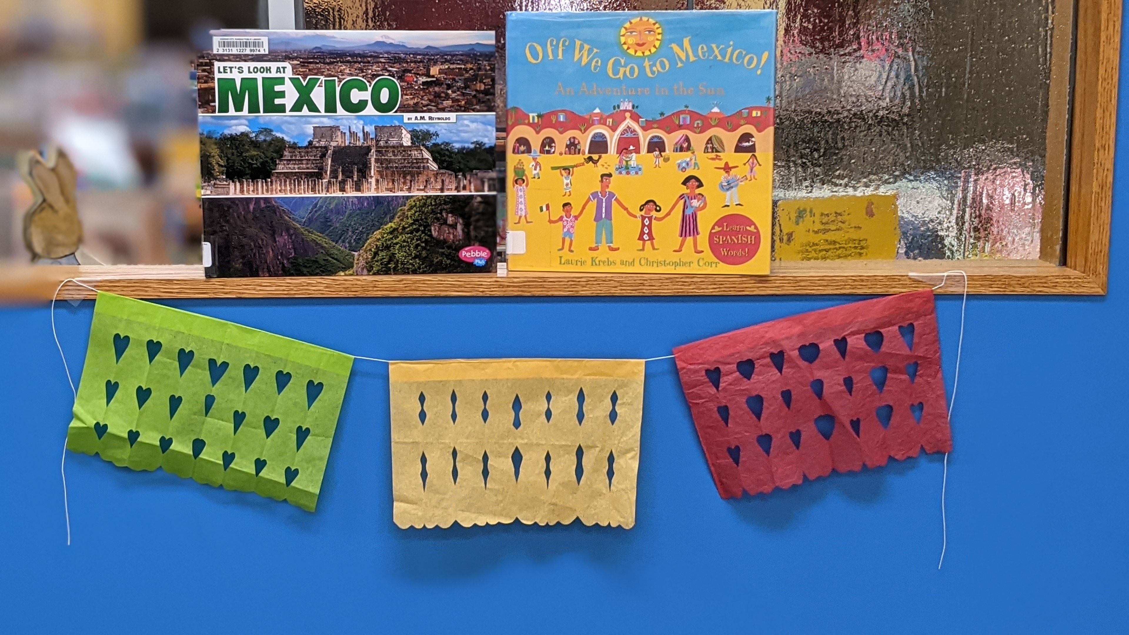 Display of books about Mexico and a papel picado banner.