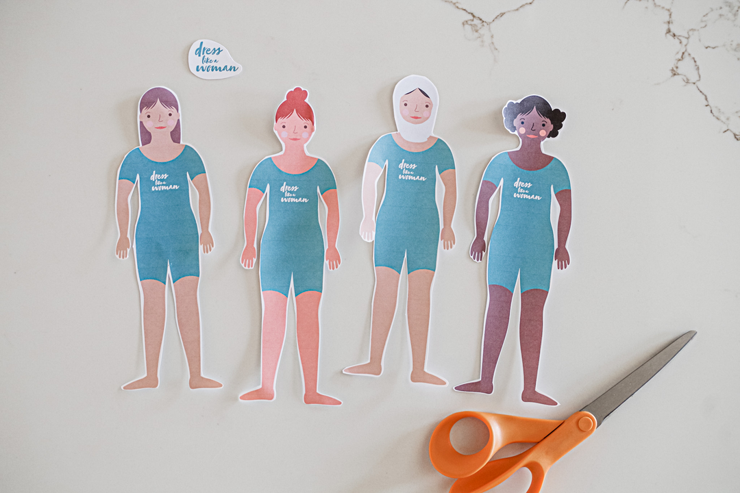 There are cut outs of four paper dolls. The first girl has light brown skin and shoulder-length brown hair. The second girl has light skin and red hair in a bun. The third girl has light skin and wears a white hijab. The fourth girl has dark skin and curly hair in two buns on the side of her head. 