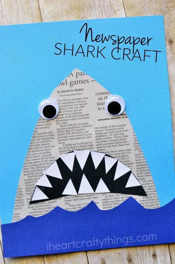 A shark made of newspaper has a cut out teeth and mouth in the ocean. 