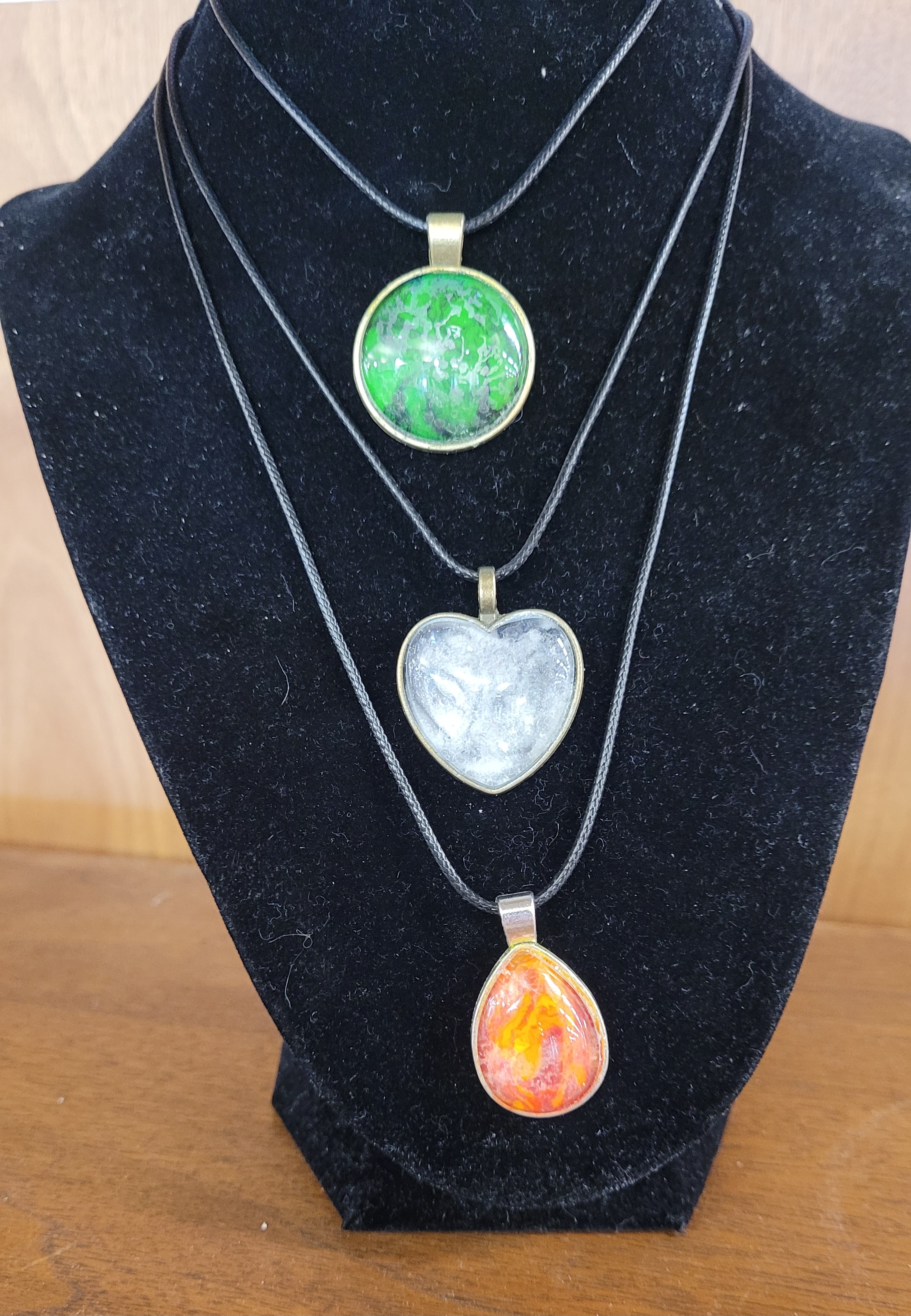 Three colored necklaces on a black display stand.