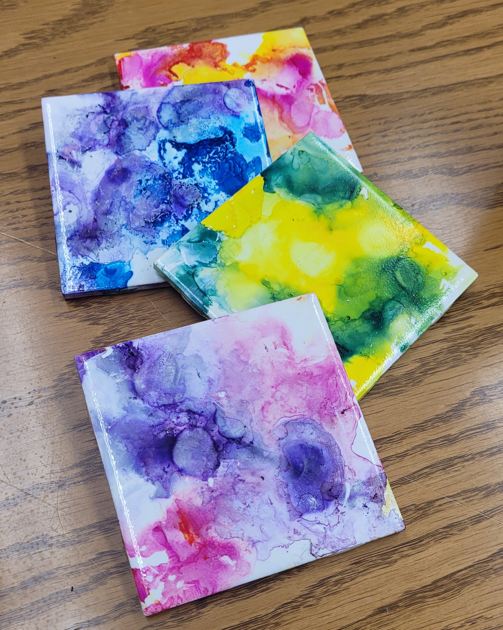 4 tile coasters with tie dye patterns on them