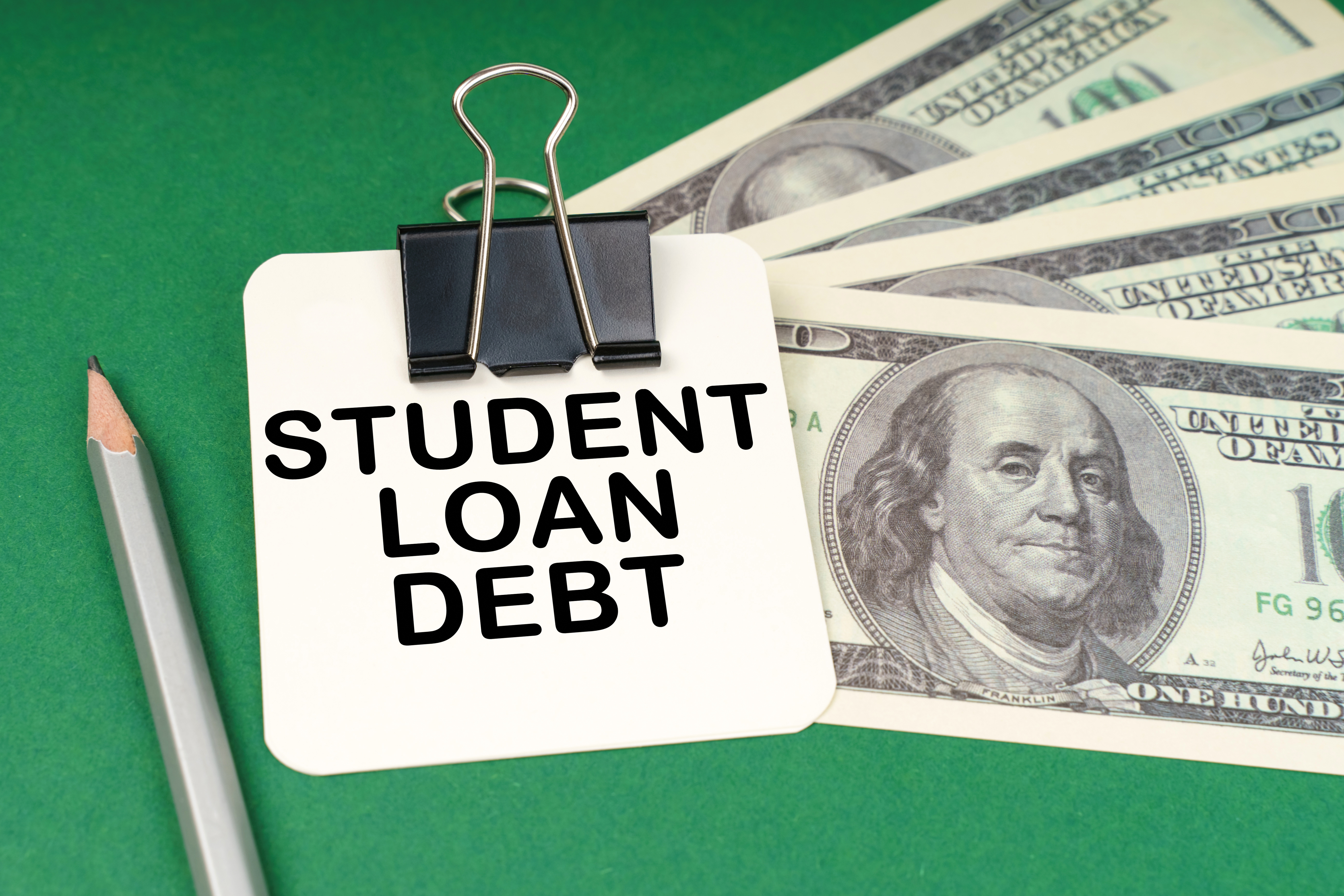 Student Loan Debt written note on a stack of 100-dollar bills
