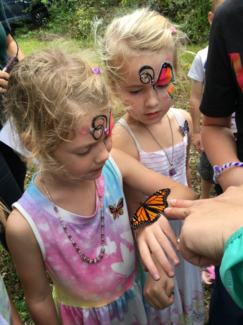 Two children with blonde hair with Monarch painted on their face. 