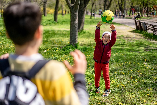 Two children throwing a green soccer ball back and forth outdoors. 