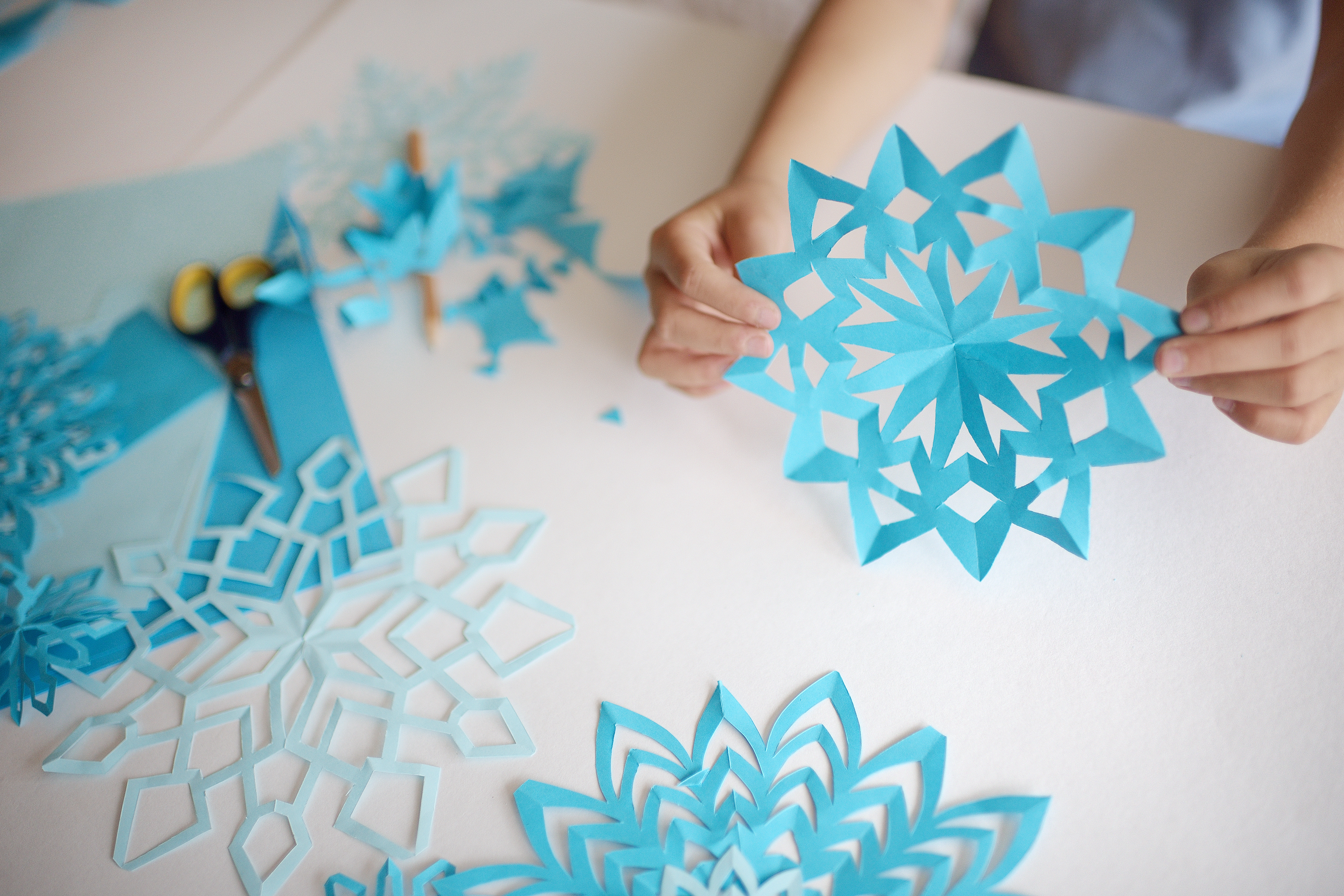 child's hands holding paper snowflake