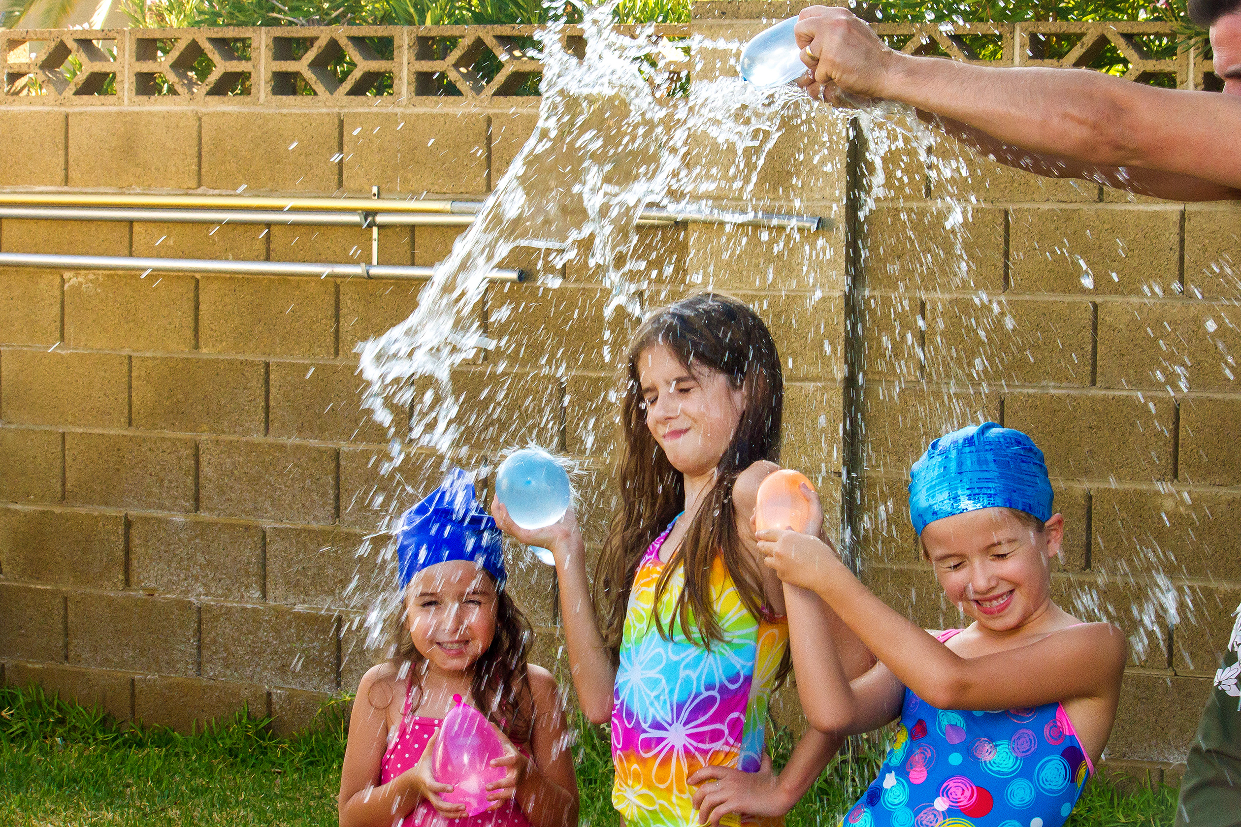three children playing with water balloons