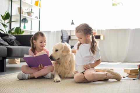 Two children reading to a dog