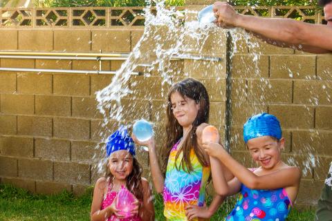 three children playing with water balloons