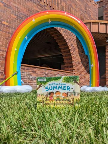 A Summer book with a Rainbow Sprinkler behind 