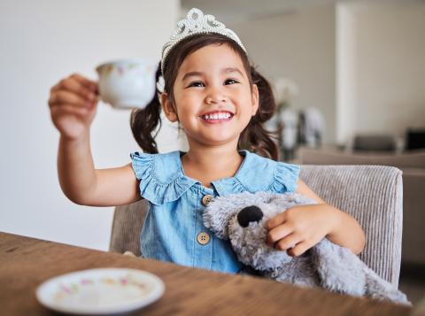 little girl in a princess crown holding a tea cup