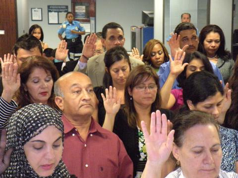 Group of individuals raising their hands to take the citizenship oath