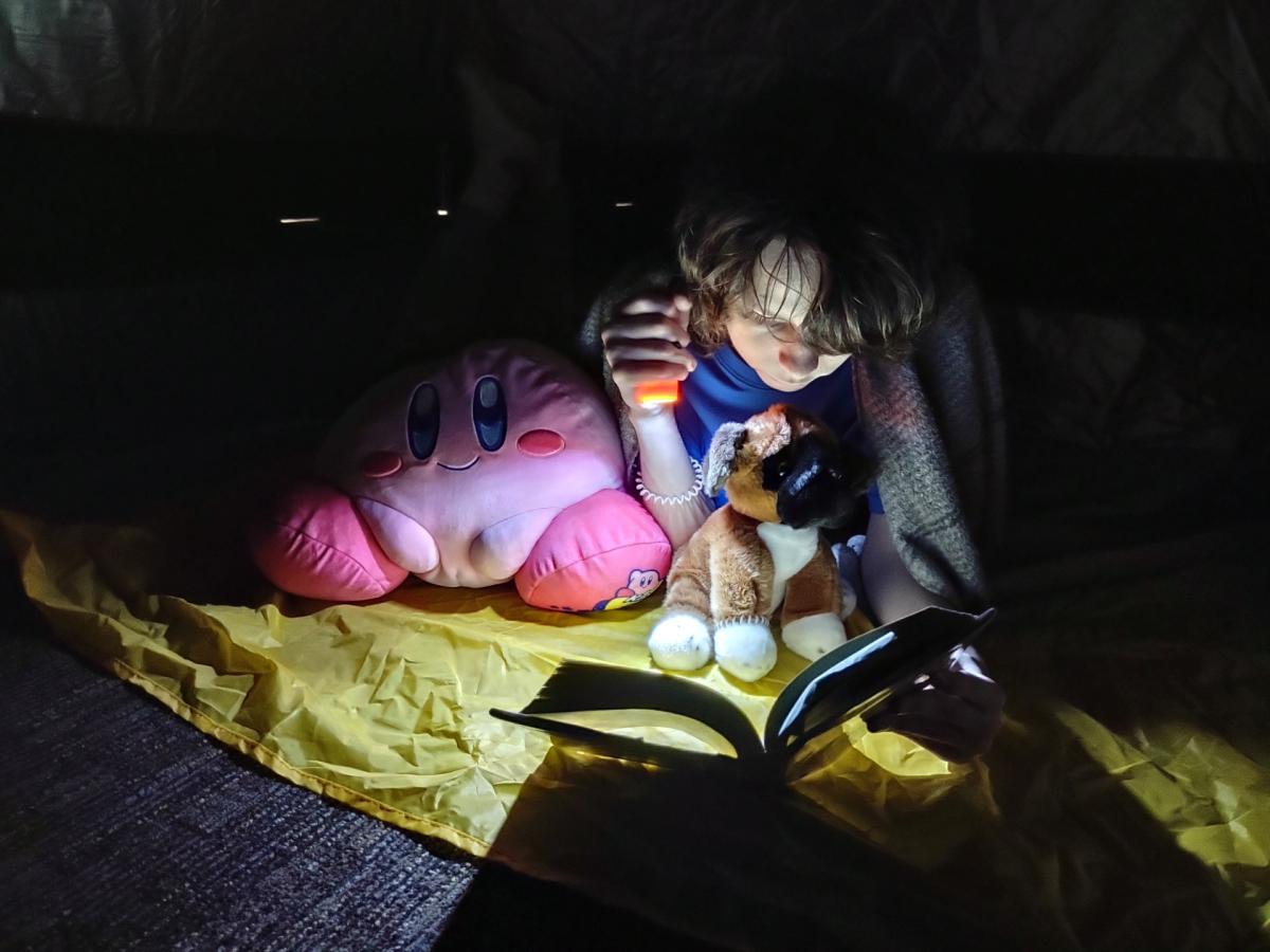 Student reading a book in a tent.